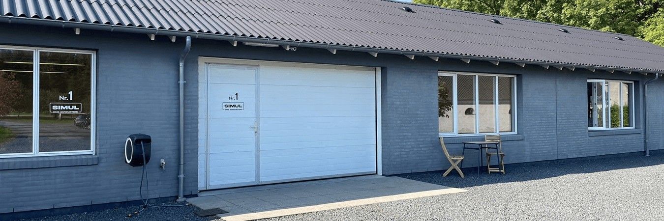 SIMUL's building at Ravnsbjergvej 1 in Veksø: gray brick, a white door marked Nr. 1 SIMUL